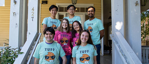 From Global Research Institute: Students and faculty on the porch of a yellow house wearing matching Tuff Cookies tshirts
