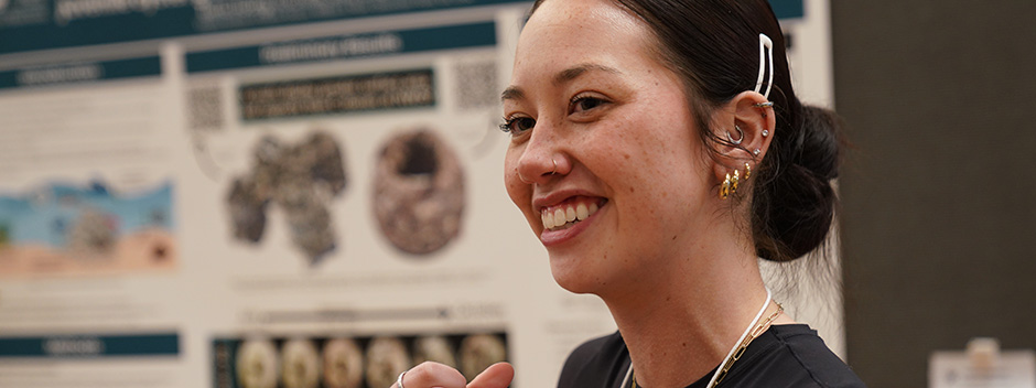 A student stands in front of their research poster about oysters