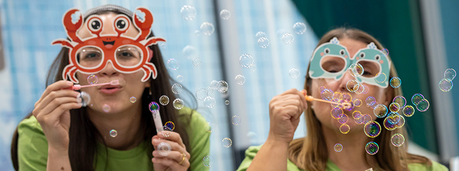 Two people in colorful marine-themed masks blow bubbles