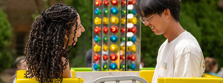 Two smiling students in the carnival's Turbo Tub spinning ride in the Sunken Garden