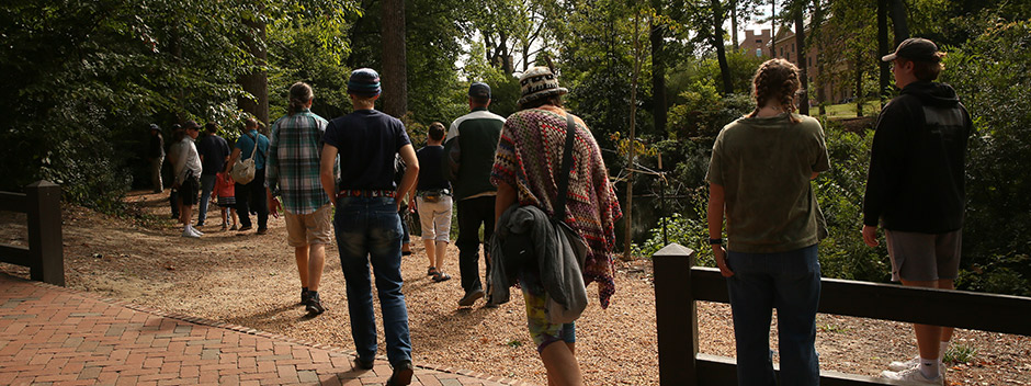 A group tours the gravel trails through the woods at the center of campus