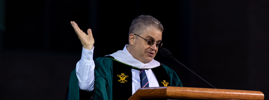 Patton Oswalt delivering his Commencement address on stage in regalia