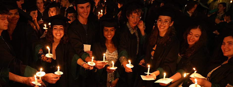  Crowd of graduates at night holding candles and smiling