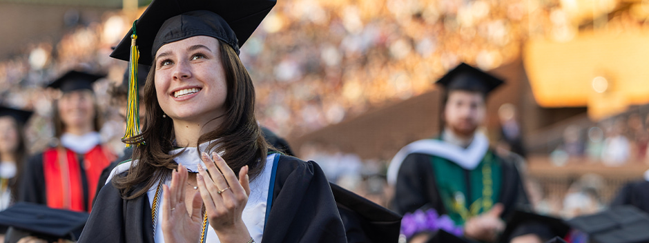 A graduate watches the stage from the field of Zable Stadium during the main ceremony 