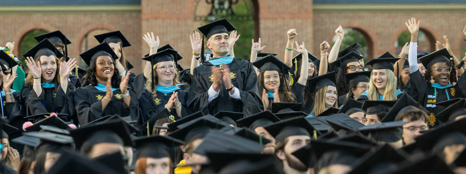 Large group of cheering graduates in full regalia near Zable stadium