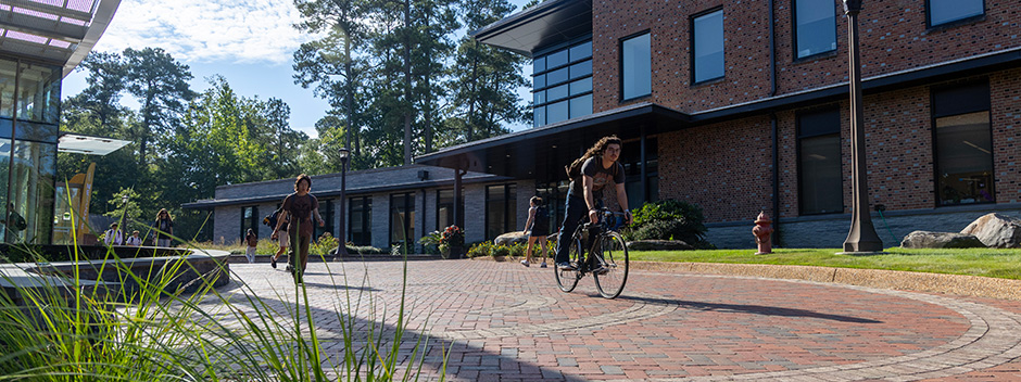 Students pass between the Sadler Center and Wellness Center along a wide brick walkway on a beautiful fall day.