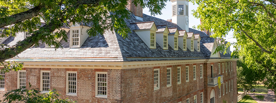 Aerial view of the Wren Building top stories, roof and cupula with lush green leaves on tree branches framing the view