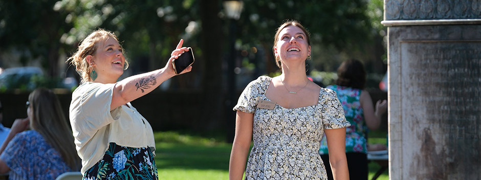 Two employees looking up at the Lord Bot statue in the Wren Yard