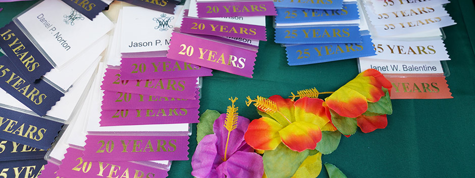 A table of prepared nametags with colorful stickers displaying 15, 20, 25 and 35 years of service