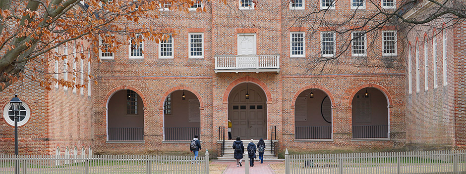 Students in winter attire walking into the historic Wren Building on an overcast day winter day