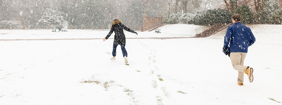 Two students tromp through a blanket of snow in the Sunken Garden following earlier footsteps left by others