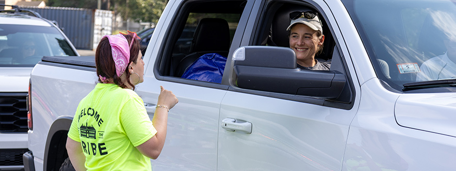A staff member talking to a family member in the passenger seat of a pickup
