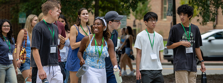 Group of new students wearing lanyards walk across campus together