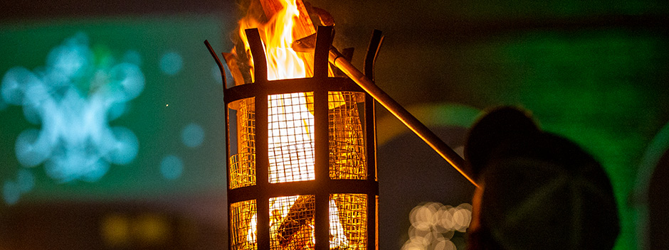 A W&amp;M employee adds wood to a burning cresset in the Wren Courtyard